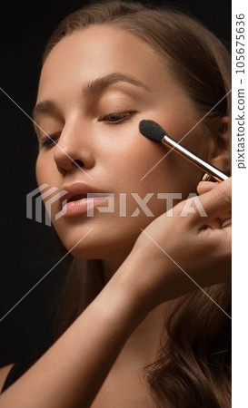 Beautiful young woman with a light natural make-up, brush for cosmetics and perfect skin. 105675636