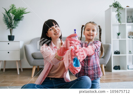 Family team in pink gloves reaching out spray cleaner on rug Family team in pink gloves reaching out spray cleaner on rug 105675712