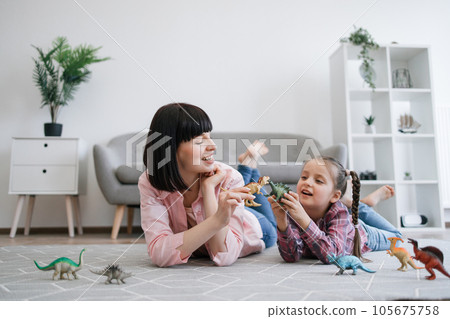 Tween girl having fun with mom via animal game toys indoors Tween girl having fun with mom via animal game toys indoors 105675758