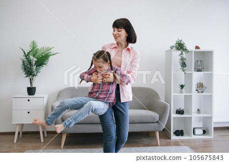 Mom twirling daughter around while staying indoors on day 105675843