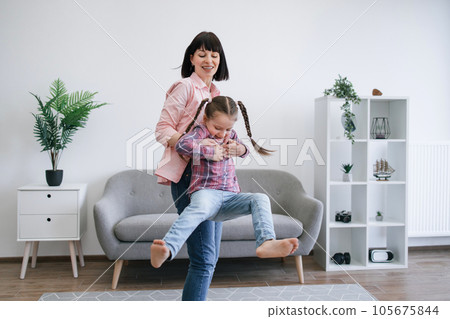 Mom twirling daughter around while staying indoors on day 105675844