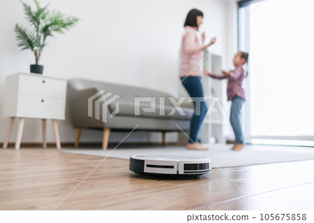 Robotic device collecting dust while mom and child dancing 105675858