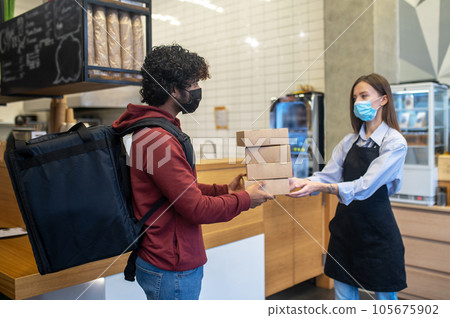 Curly-haired male courrier taking orders from the cafe 105675902