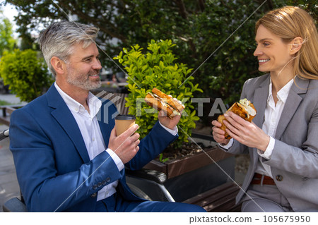 Colleagues wearing suits having lunch break, drinking coffee and eating. Colleagues wearing suits having lunch break, drinking coffee and eating. 105675950