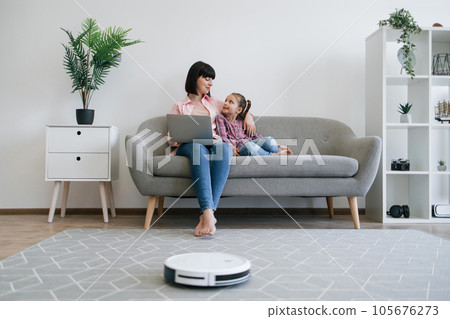 Family ladies resting with laptop when robot cleaner working Family ladies resting with laptop when robot cleaner working 105676273
