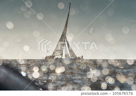 The view through the spray of how the two sailboats are heeling at sunset, boat roll, splashes shine in the sun, sailors on the boards 105676578