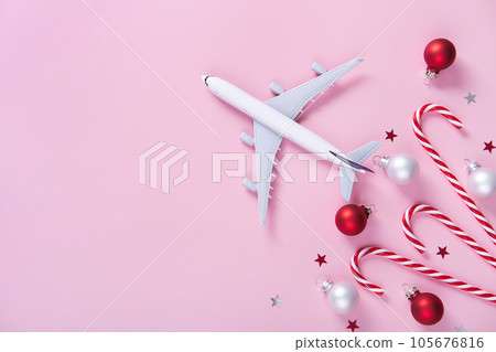 Christmas travel concept. Model of passenger plane and candy canes on pink background Christmas travel concept. Model of passenger plane and candy canes on pink background 105676816