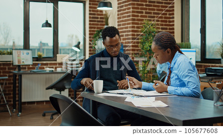 Department members reviewing paperwork in boardroom office, meeting to discuss new business startegy. Startup agency employees collaborating on management vision, research project. 105677608