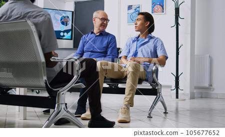 Patients discussing disease expertise, sitting on chiar in hospital reception waiting to attend medical consultation with physician during checkup visit. Health care service and support 105677652