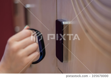 A woman opens the electronic lock of a cubicle in a locker room with a bracelet. A woman opens the electronic lock of a cubicle in a locker room with a bracelet. 105678000