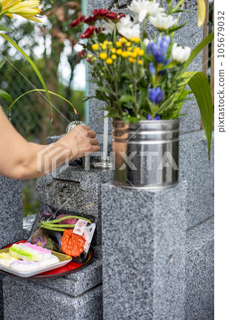 Hand of a senior woman who is giving incense after visiting a grave 105679032