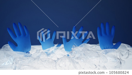 Marine pollution. Earth contamination. Blown medical gloves drowning in abstract ice water from crushed wet plastic bottles pile isolated on blue background empty space. 105680824