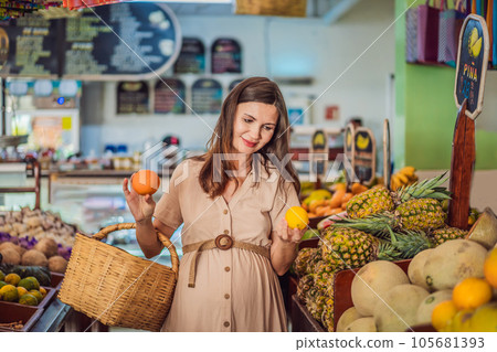 A glowing pregnant woman after forty makes a healthy choice as she selects organic vegetables and fruits at the vibrant organic market, prioritizing her well-being and her baby's health 105681393