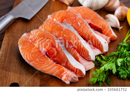 Raw salmon steaks with lemon, parsley, garlic Raw salmon steaks with lemon, parsley, garlic 105681752