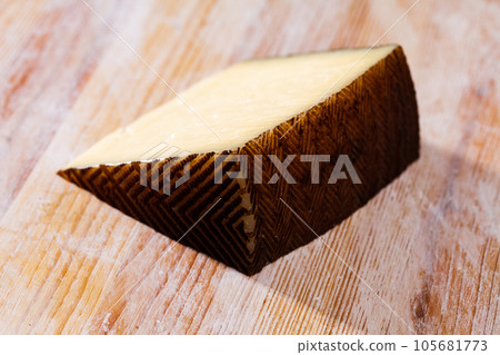 Slice of semi hard cheese on wooden surface Slice of semi hard cheese on wooden surface 105681773