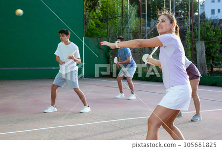 Portrait of sporty girl playing paleta fronton on outdoor court, ready to hit ball. Healthy and active lifestyle concept 105681825