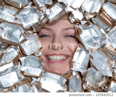 The face of a Caucasian woman surrounded by candy wrappers.  105682012