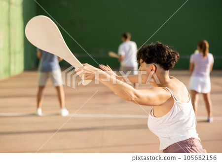 Sporty woman performing basic strokes during paleta fronton group training 105682156