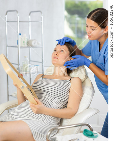 Young woman cosmetologists examines face of female patient 105682246
