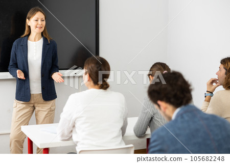 Positive successful woman near interactive board conducting business training for audience in classroom 105682248