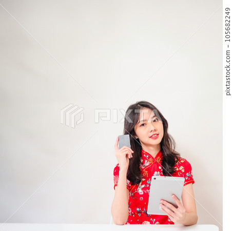 Asian young woman wearing traditional cheongsam(qipao) dress using digital tablet and credit card shopping online, e-commerce concept isolated on white background. 105682249