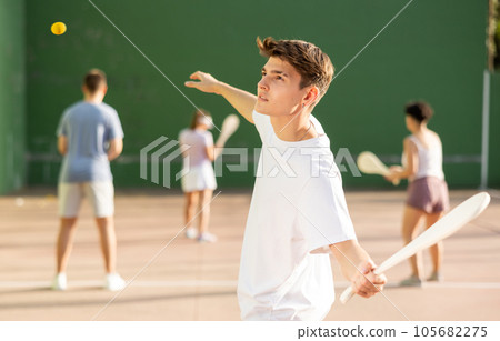 Concentrated young man paleta fronton player hitting ball with racket 105682275