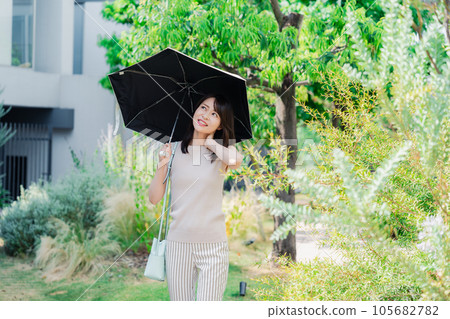 年輕女子打著陽傘在外面散步 年輕女子打著陽傘在外面散步 105682782