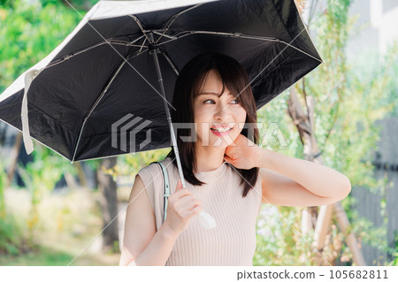 年輕女子打著陽傘在外面散步 年輕女子打著陽傘在外面散步 105682811