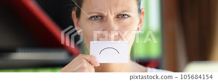 Frustrated woman covered her mouth with paper with sad emoticon. 105684154