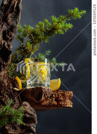 Cocktail gin-tonic with lemon in a crystal glass on an old board. Cocktail gin-tonic with lemon in a crystal glass on an old board. 105684529