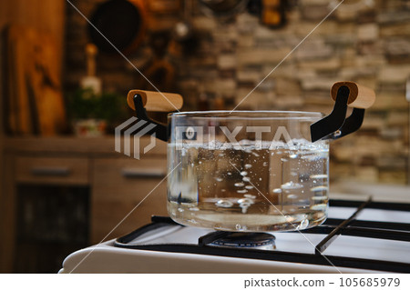 Water boiling in glass pot on stove 105685979