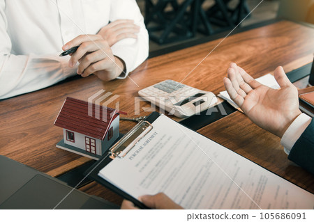 Business people home sales broker is using a pen pointing to the house model and describing the various components of the house. Business people home sales broker is using a pen pointing to the house model and describing the various components of the house. 105686091
