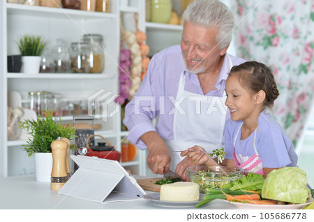 Senior man with granddaughter preparing dinner 105686778