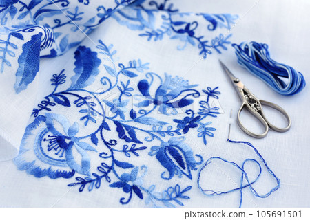 Embroidery, thread and scissors. Blue floral ornament on a white background. Embroidery, thread and scissors. Blue floral ornament on a white background. 105691501