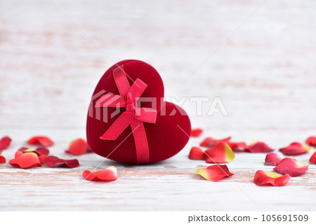 Heart-shaped gift box with petals on a light wooden background. Valentines Day background 105691509