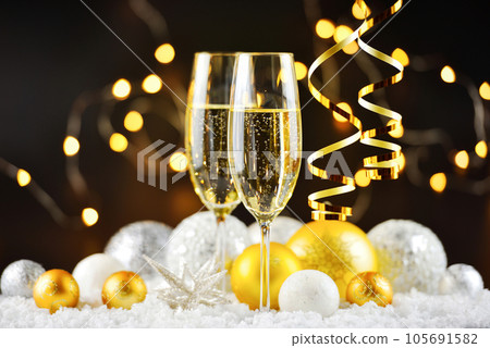 Two champagne glasses and christmas decorations on snow on a dark festive background. 105691582