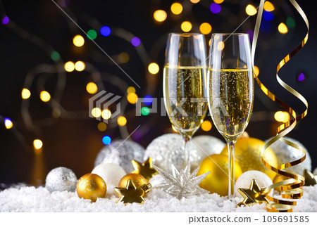 Two champagne glasses and christmas decorations on snow on a dark festive background.  105691585