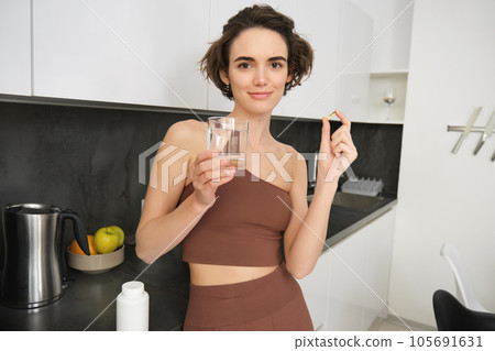 Diet. Nutrition. Healthy Eating, Lifestyle. Close Up Of Happy Smiling Woman Taking Pill With Cod Liver Oil Omega-3 And Holding A Glass Of Fresh Water In Morning. Vitamin D, E, A Fish Oil Capsules Diet. Nutrition. Healthy Eating, Lifestyle. Close Up Of Happy Smiling Woman Taking Pill With Cod Liver Oil Omega-3 And Holding A Glass Of Fresh Water In Morning. Vitamin D, E, A Fish Oil Capsules 105691631