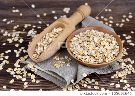 Oatmeal or oat flakes in bowl and scoop on dark wooden table 105691645