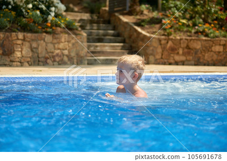 Young boy kid child eight years old splashing in swimming pool having fun leisure activity. Boy happy swimming in a pool. Activities on the pool, children swimming and playing in water, happiness and Young boy kid child eight years old splashing in swimming pool having fun leisure activity. Boy happy swimming in a pool. Activities on the pool, children swimming and playing in water, happiness and 105691678