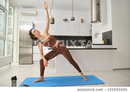 Beautiful young woman practicing yoga at home 105691694