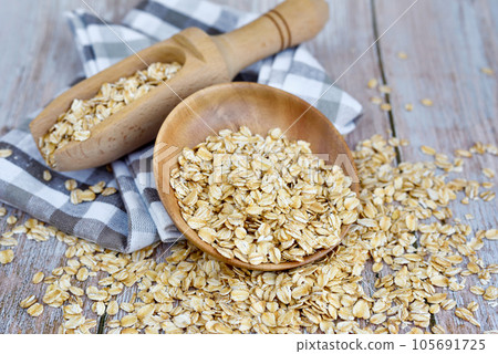Oatmeal or oat flakes in bowl and scoop on rustic table. Concept of healthy eating 105691725