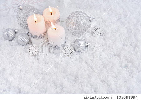 Christmas composition with festive decorative balls and candles on the snow Christmas composition with festive decorative balls and candles on the snow 105691994