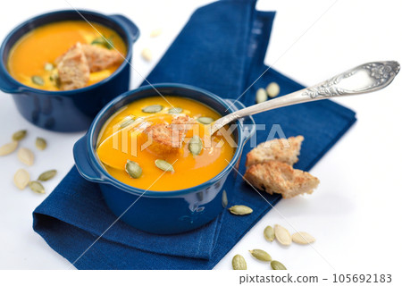 Pumpkin soup with croutons and pumpkin seeds on white background 105692183