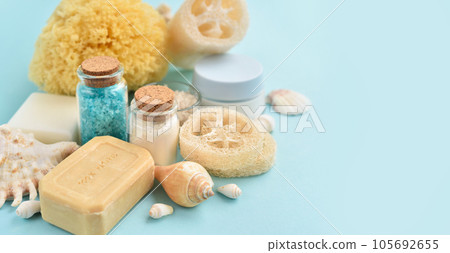 Spa accessories - sea salt, cream, sea sponge, soap and shells in cosmetics set for spa on blue 105692655