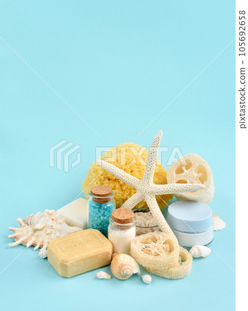 Spa accessories - sea salt, cream, sea sponge, soap and shells in cosmetics set for spa on blue 105692658