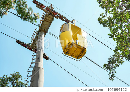 Yellow cabin of overhead cable car against blue sky Yellow cabin of overhead cable car against blue sky 105694122