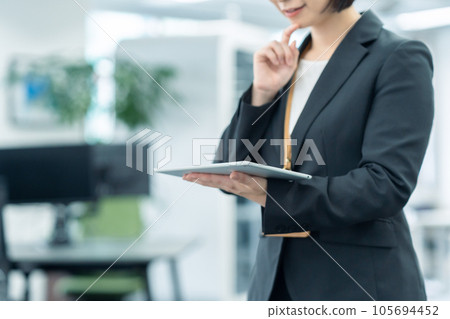 Young female businessman working with tablet in office Young female businessman working with tablet in office 105694452