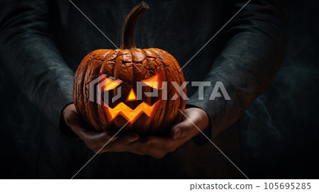 Unrecognizable man holding jack-o-lantern in hands on dark night background. Halloween concept Unrecognizable man holding jack-o-lantern in hands on dark night background. Halloween concept 105695285