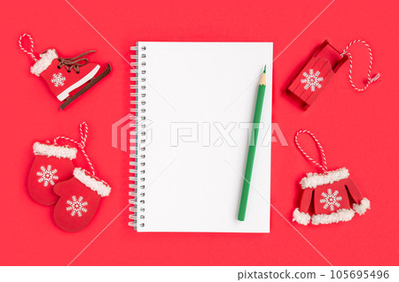 Christmas presents preparation. Notebook, pencil, decorative snowflakes, mitten, sledge, skates on red background. Xmas and Happy New Year composition. Flat lay style, top view, overhead 105695496